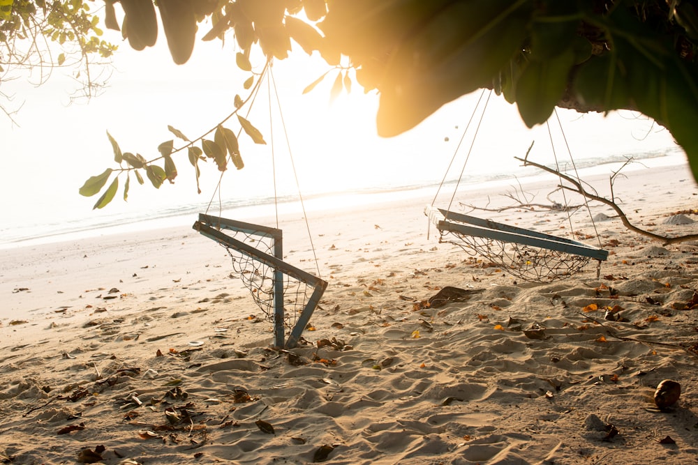 a couple of swings sitting on top of a sandy beach