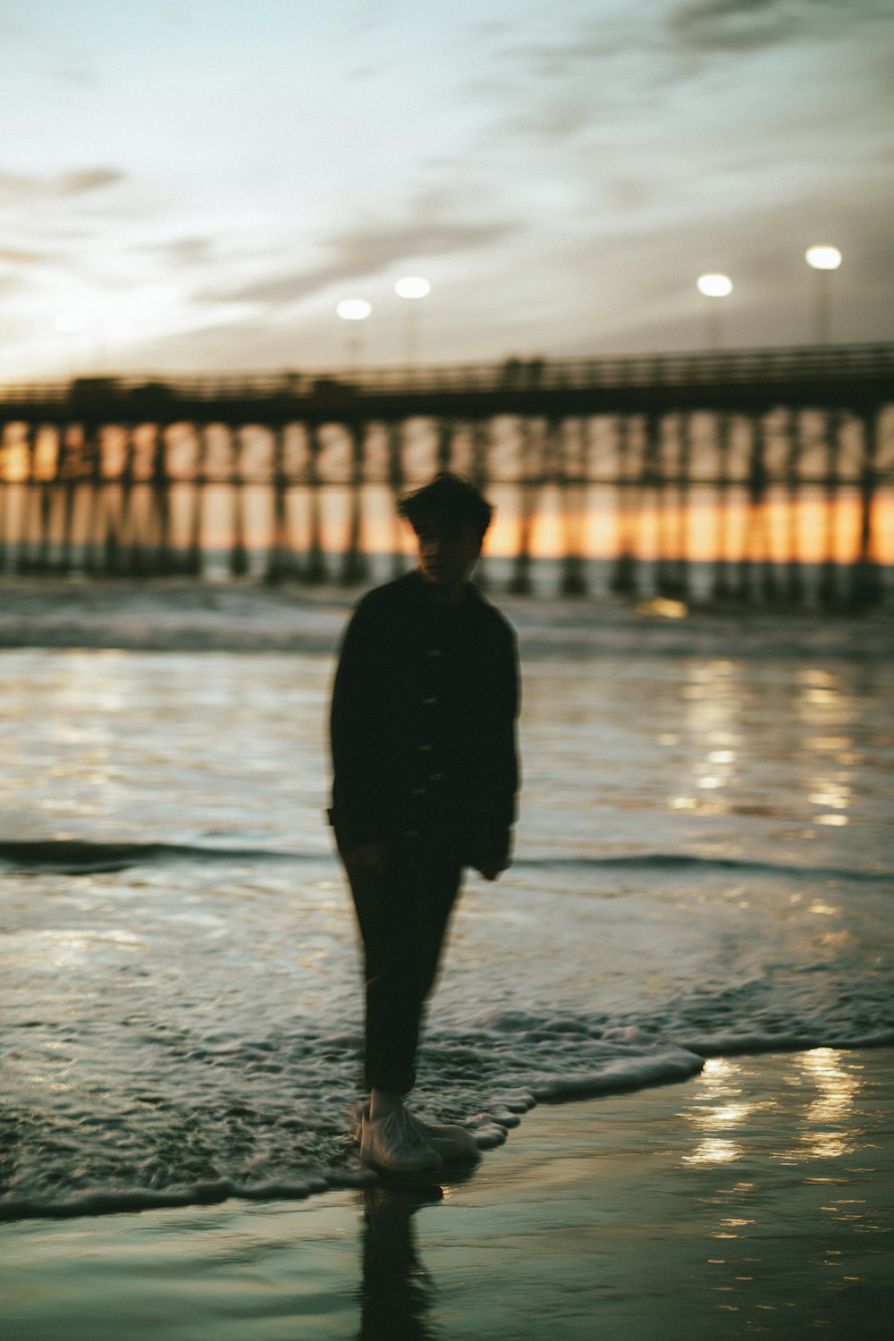 a man standing on top of a beach next to the ocean