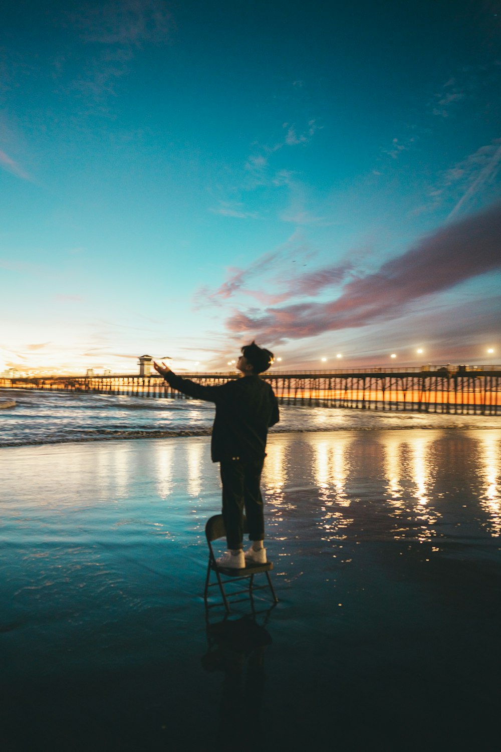 a man standing on top of a chair on top of a beach