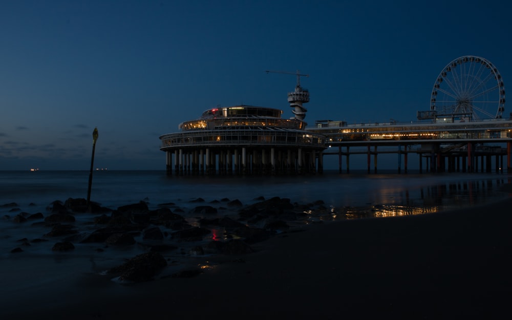 a ferris wheel sitting on top of a pier next to the ocean