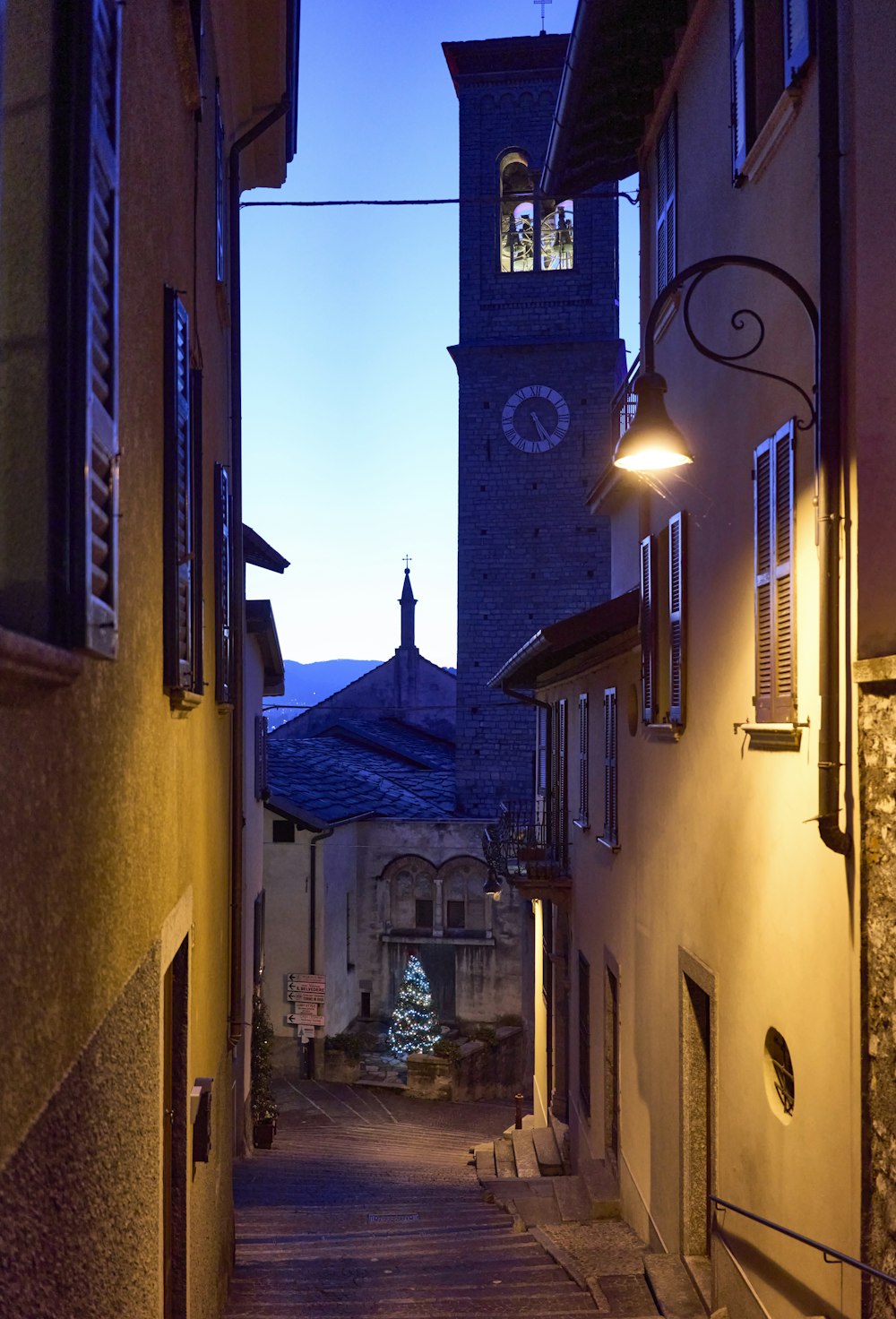 a narrow street with a clock tower in the background