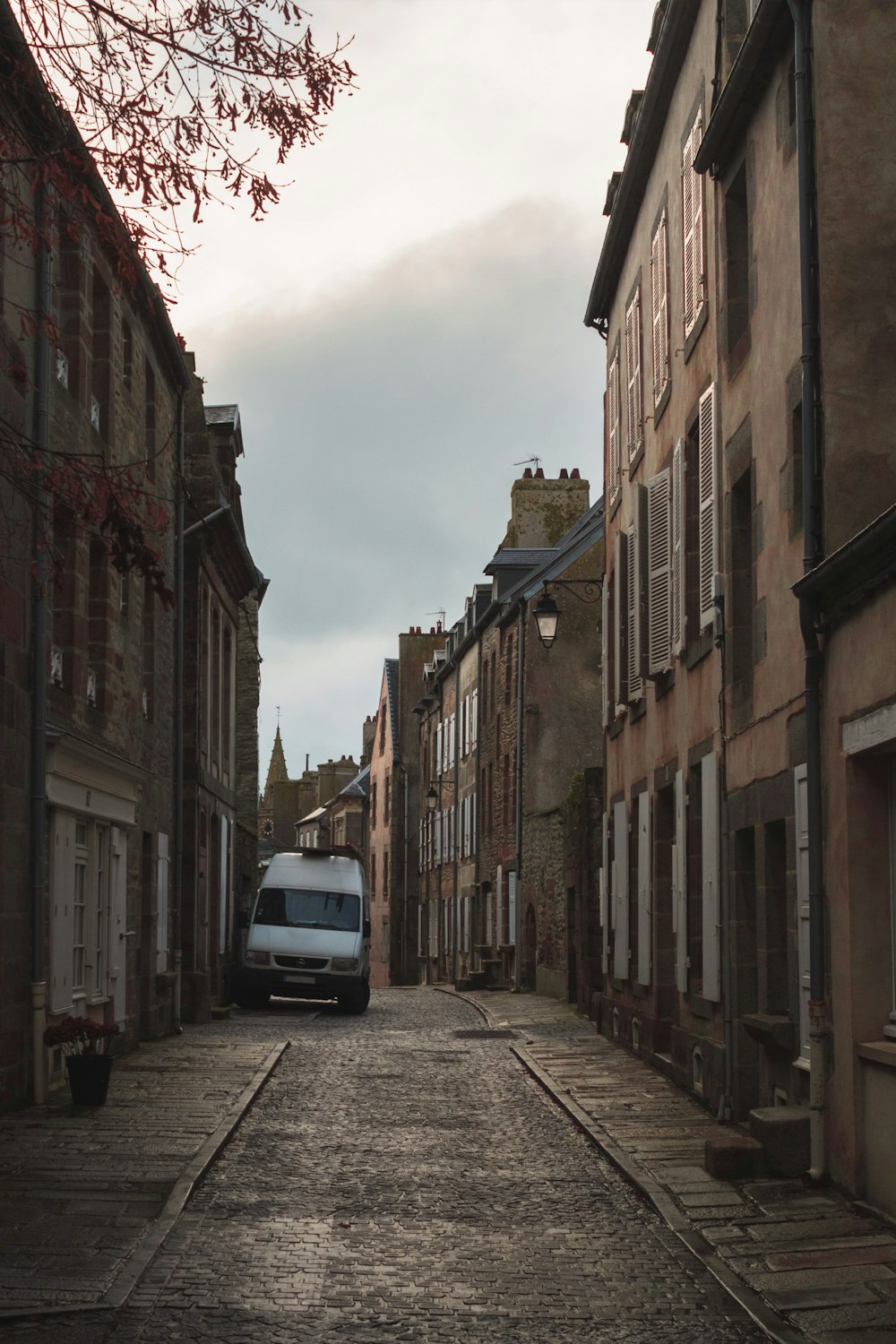 a van is parked on the side of a narrow street