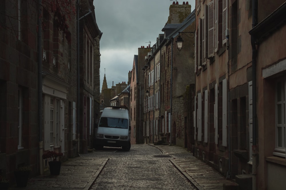 a van is parked on the side of a narrow street