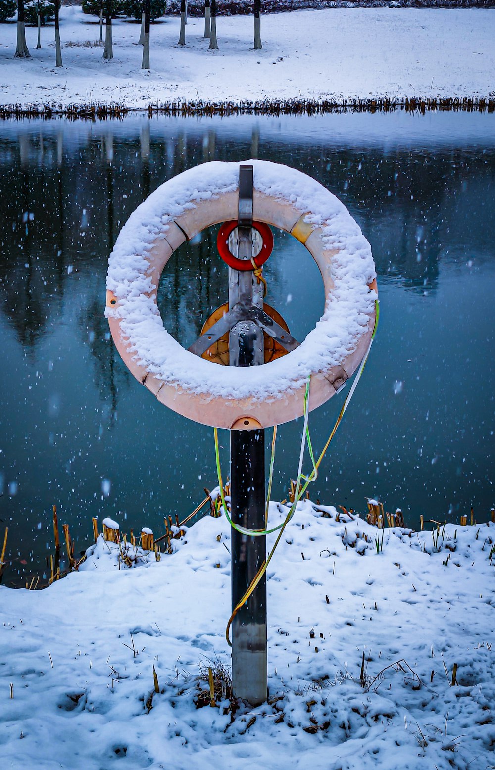 a fire hydrant covered in snow next to a lake