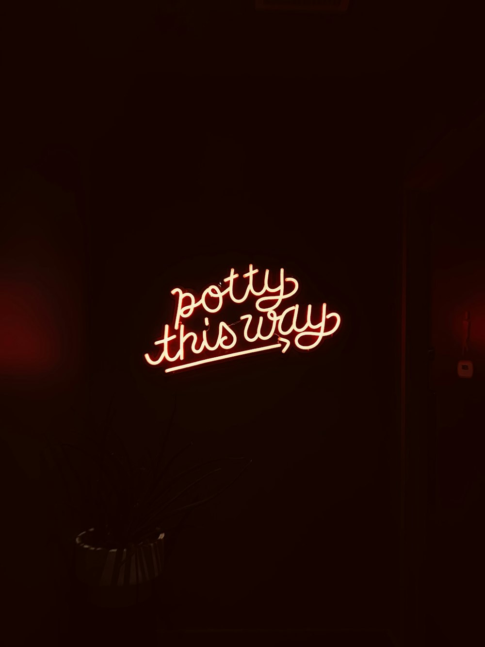 a neon sign that reads potty this way
