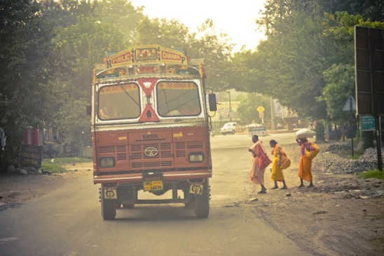 a red bus driving down a street next to a group of people