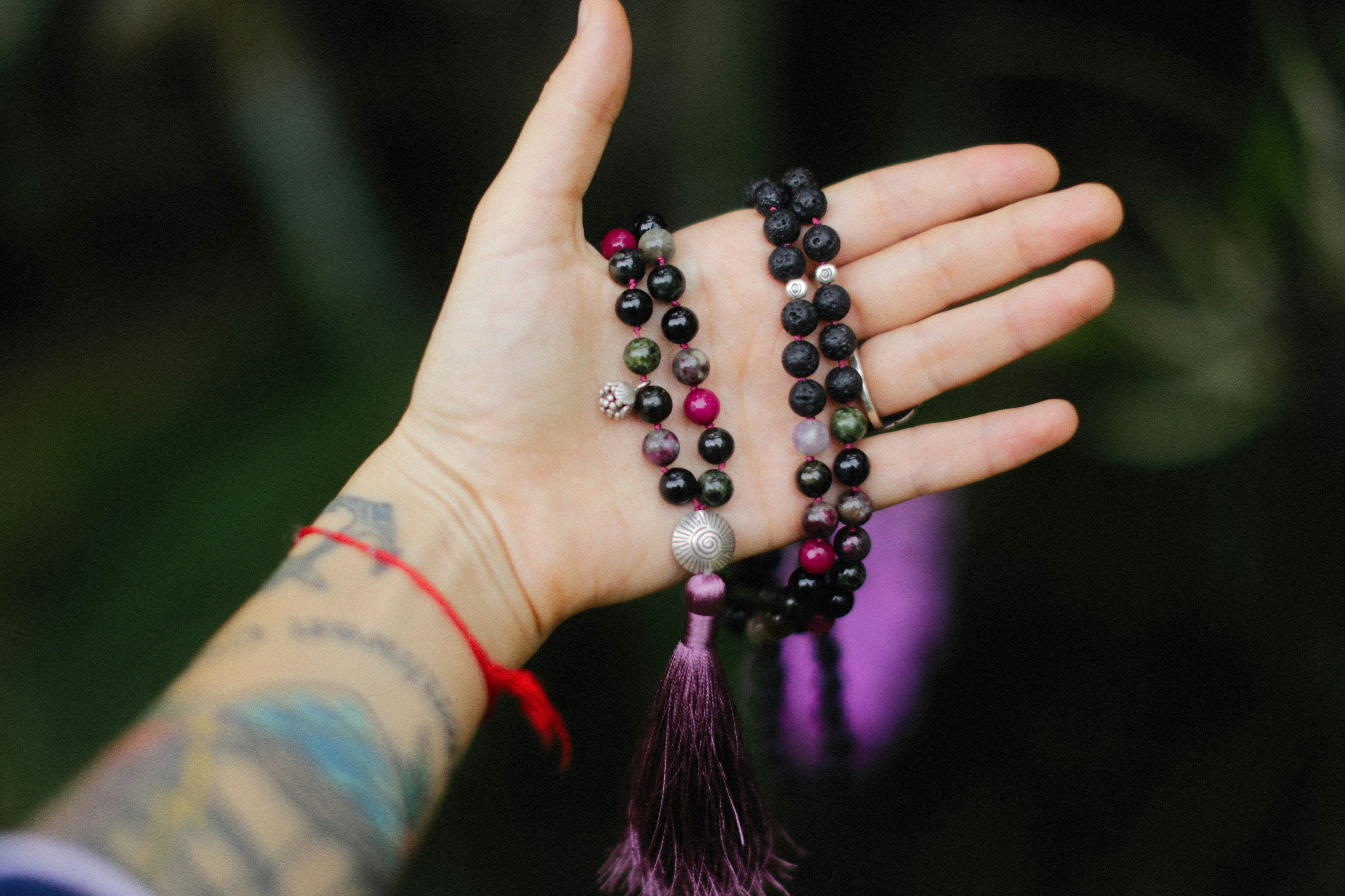 a woman's hand holding several bracelets with tassels
