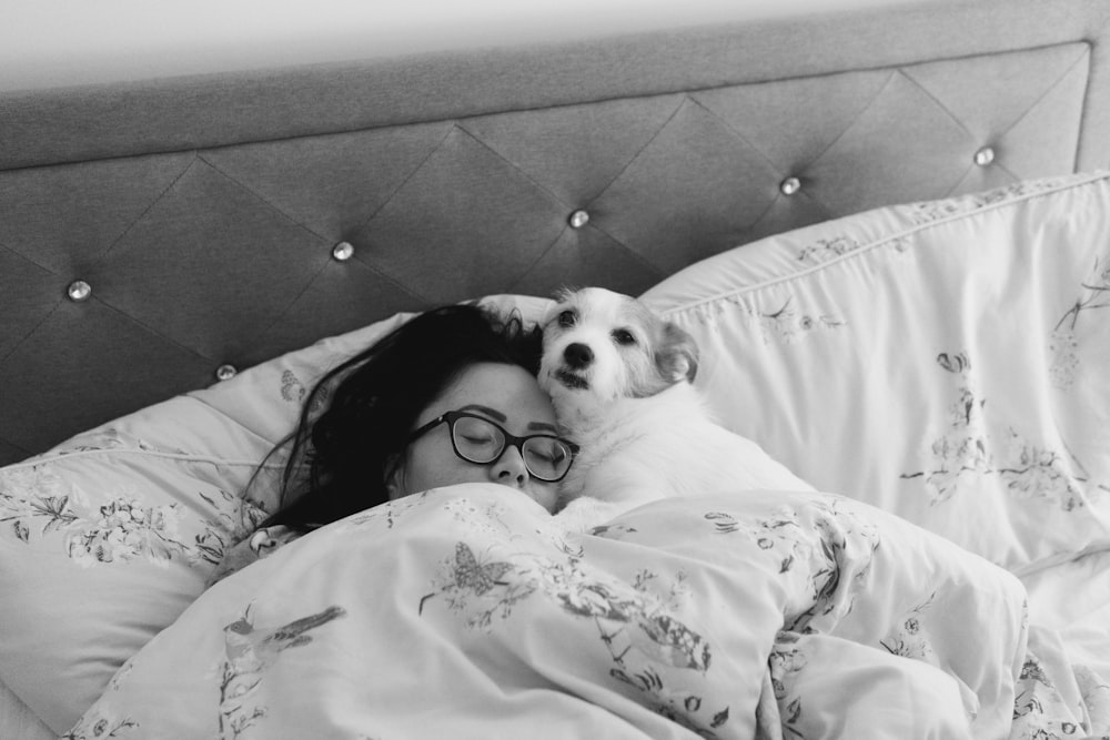 a woman laying in bed with her dog