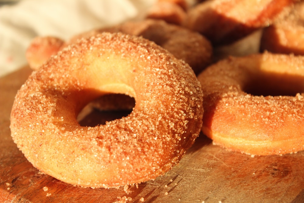 a wooden cutting board topped with sugar covered donuts