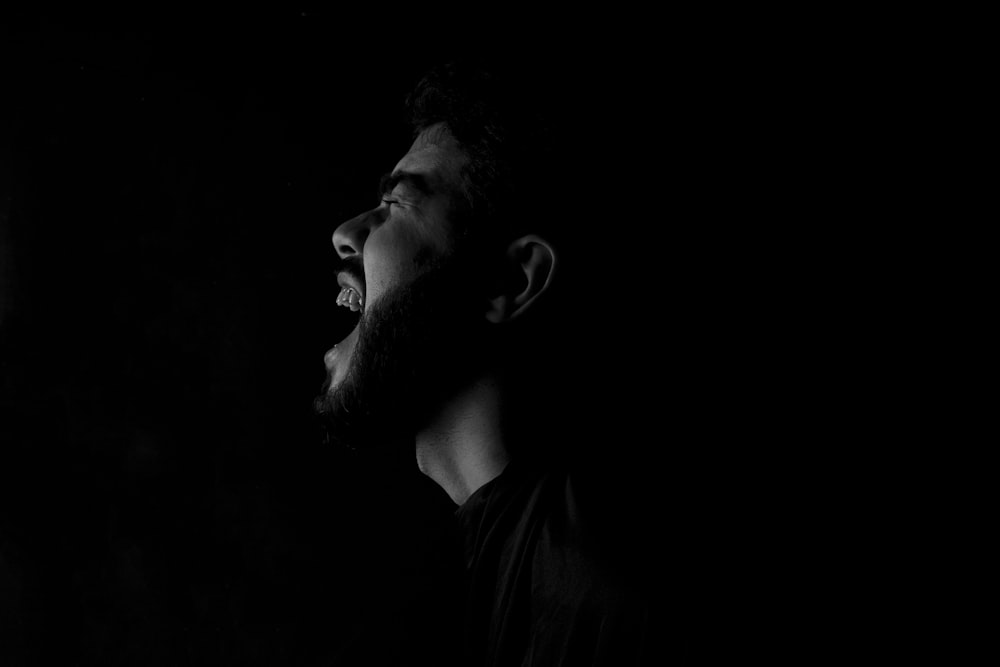 um homem com uma barba de pé no escuro