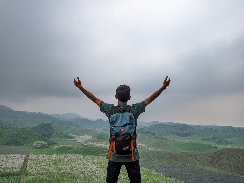 a man standing on top of a lush green hillside