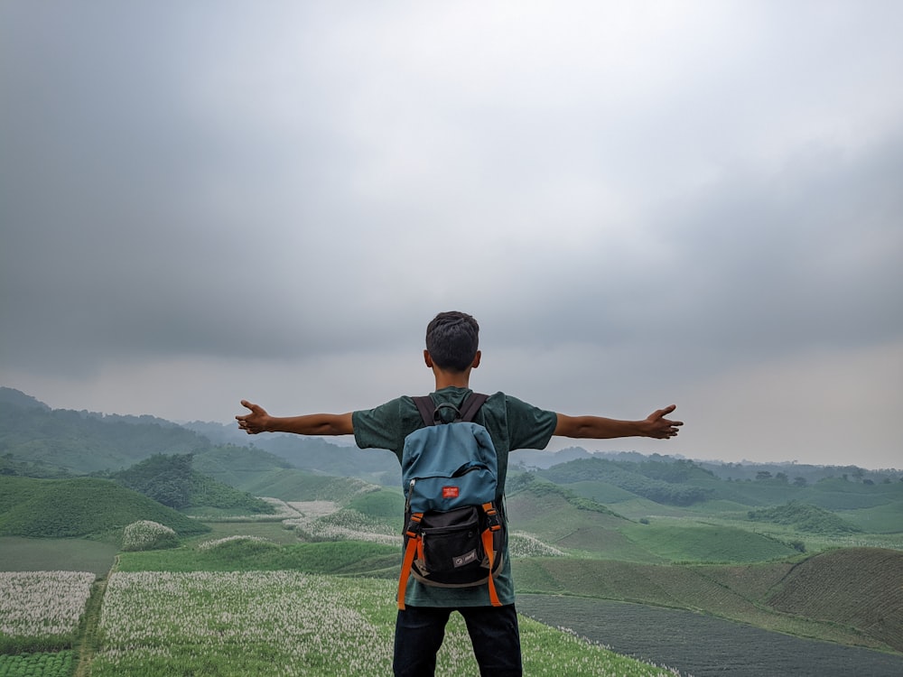 Un hombre parado en la cima de una exuberante ladera verde