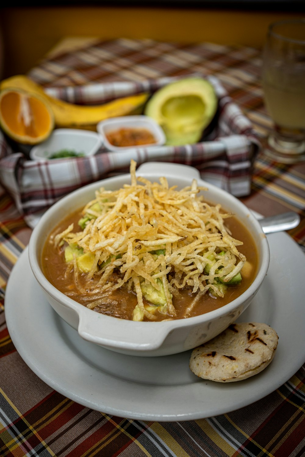 a bowl of soup on a plate with a cracker