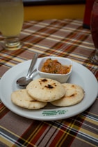 a white plate topped with food next to a bowl of salsa