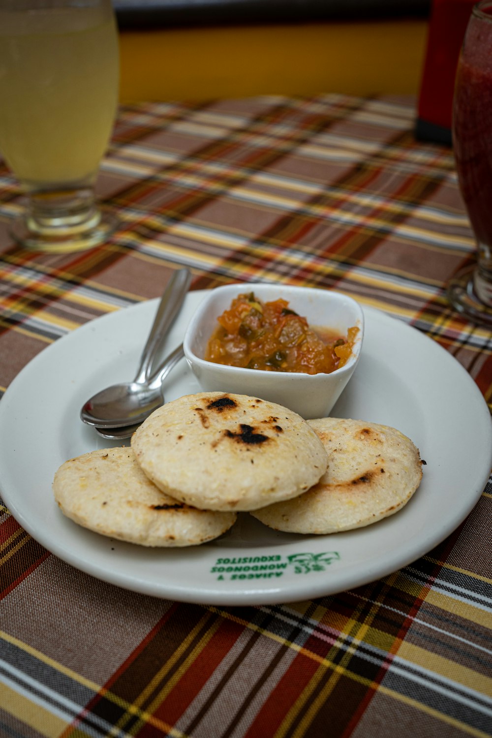 a white plate topped with food next to a bowl of salsa