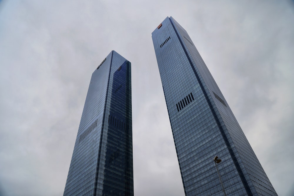 two tall skyscrapers with a cloudy sky in the background
