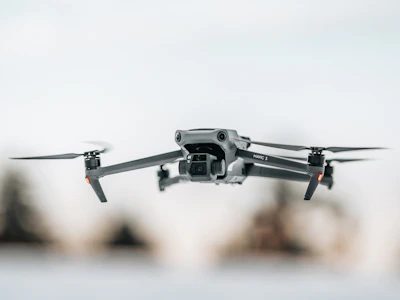 Sleek drone hovering with illuminated propellers against a black backdrop.