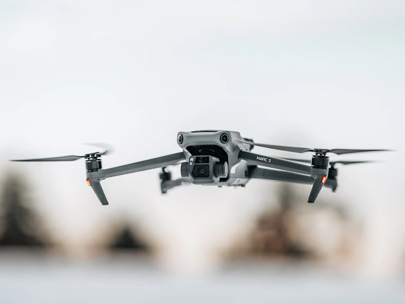 Close-up of a sleek racing drone mid-flight against a blurred urban background