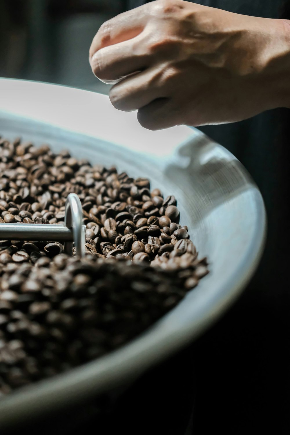 a person scooping coffee beans into a bowl