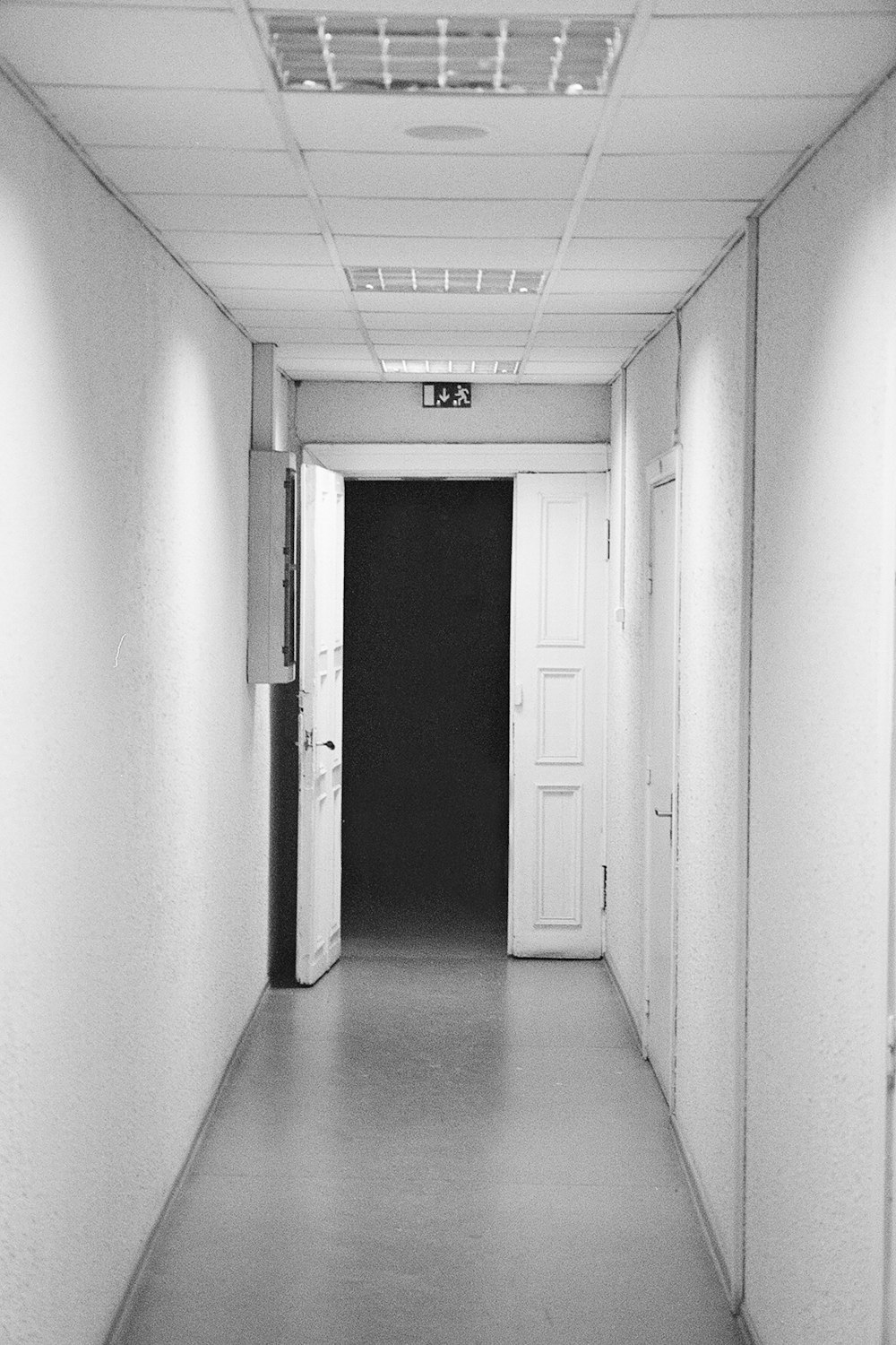 a long hallway with white walls and a black door