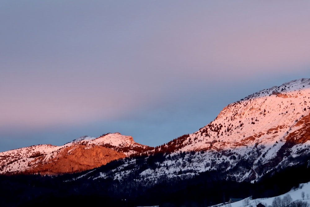 a snow covered mountain with a pink sky in the background