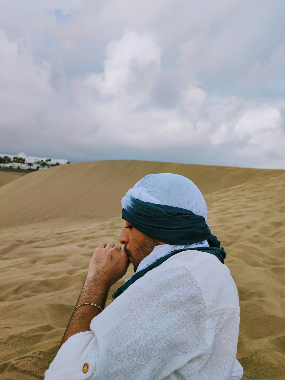 Un uomo in un turbante seduto nella sabbia