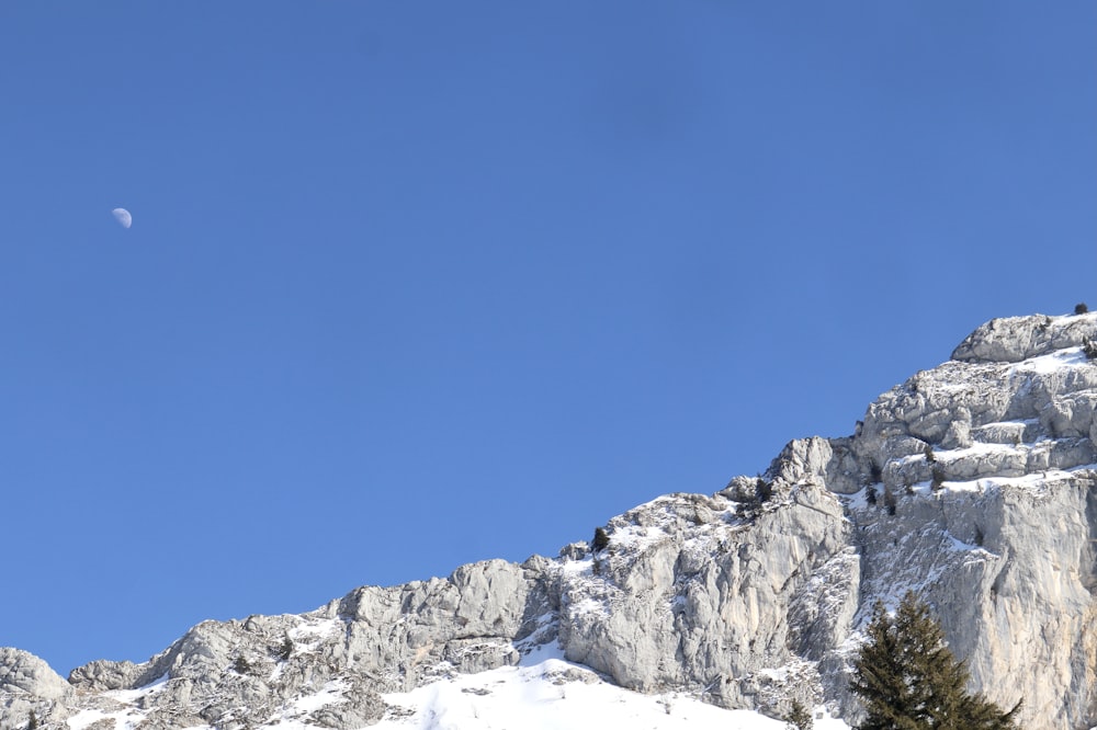 a view of a mountain with a half moon in the sky