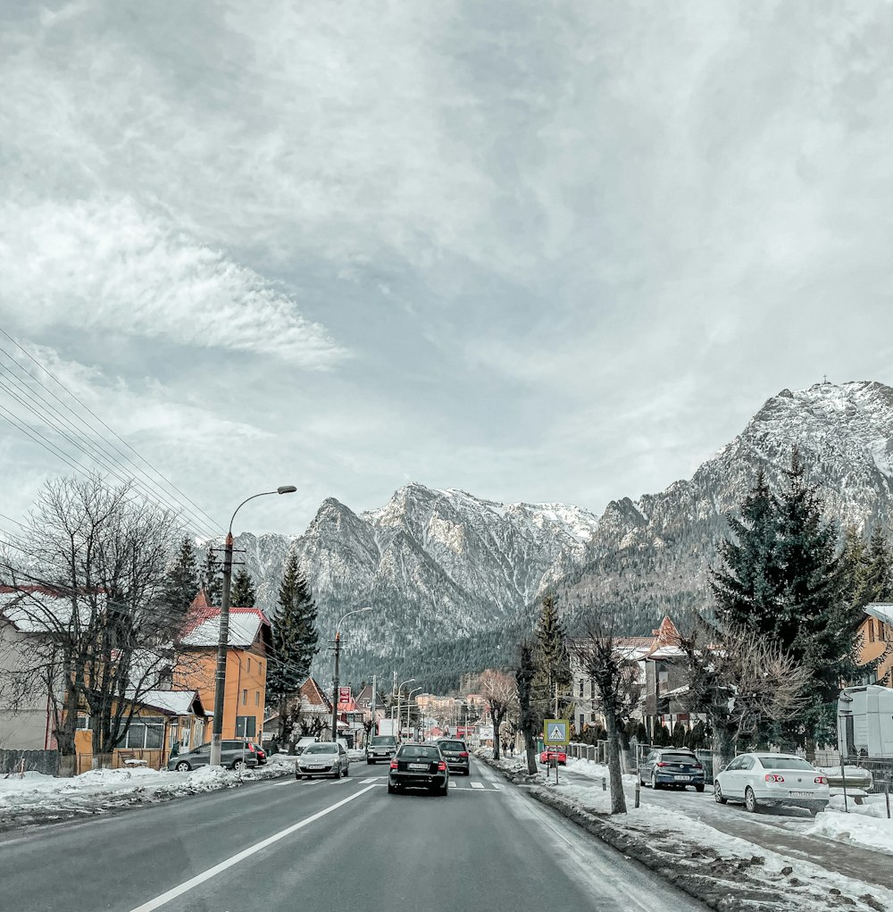 a car driving down a street next to snow covered mountains