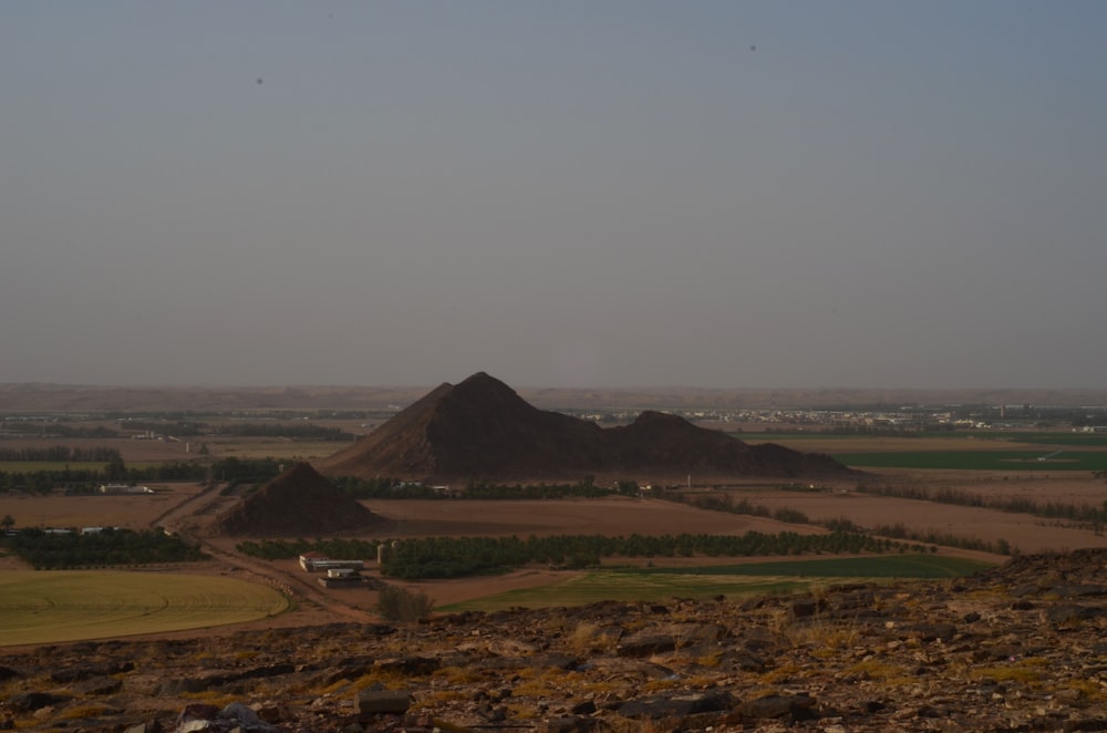 a view of a desert with a hill in the background