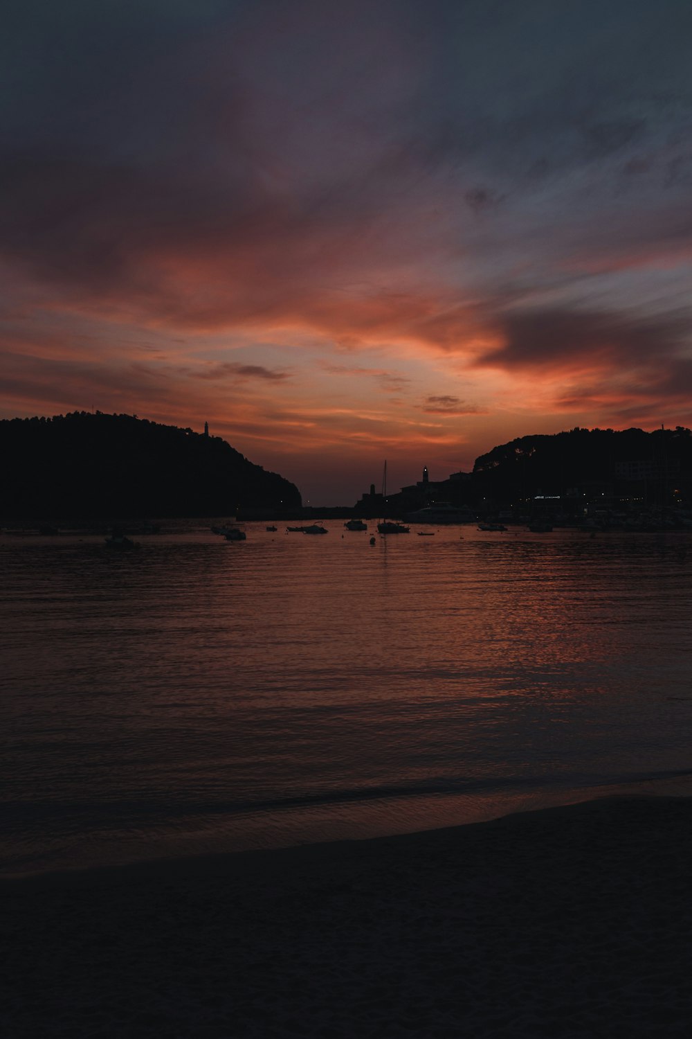 Una puesta de sol sobre un cuerpo de agua con barcos en el agua