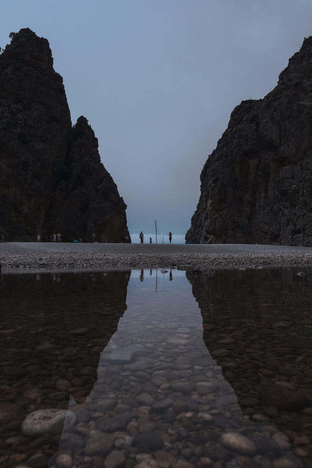 a group of people standing on a beach next to a body of water