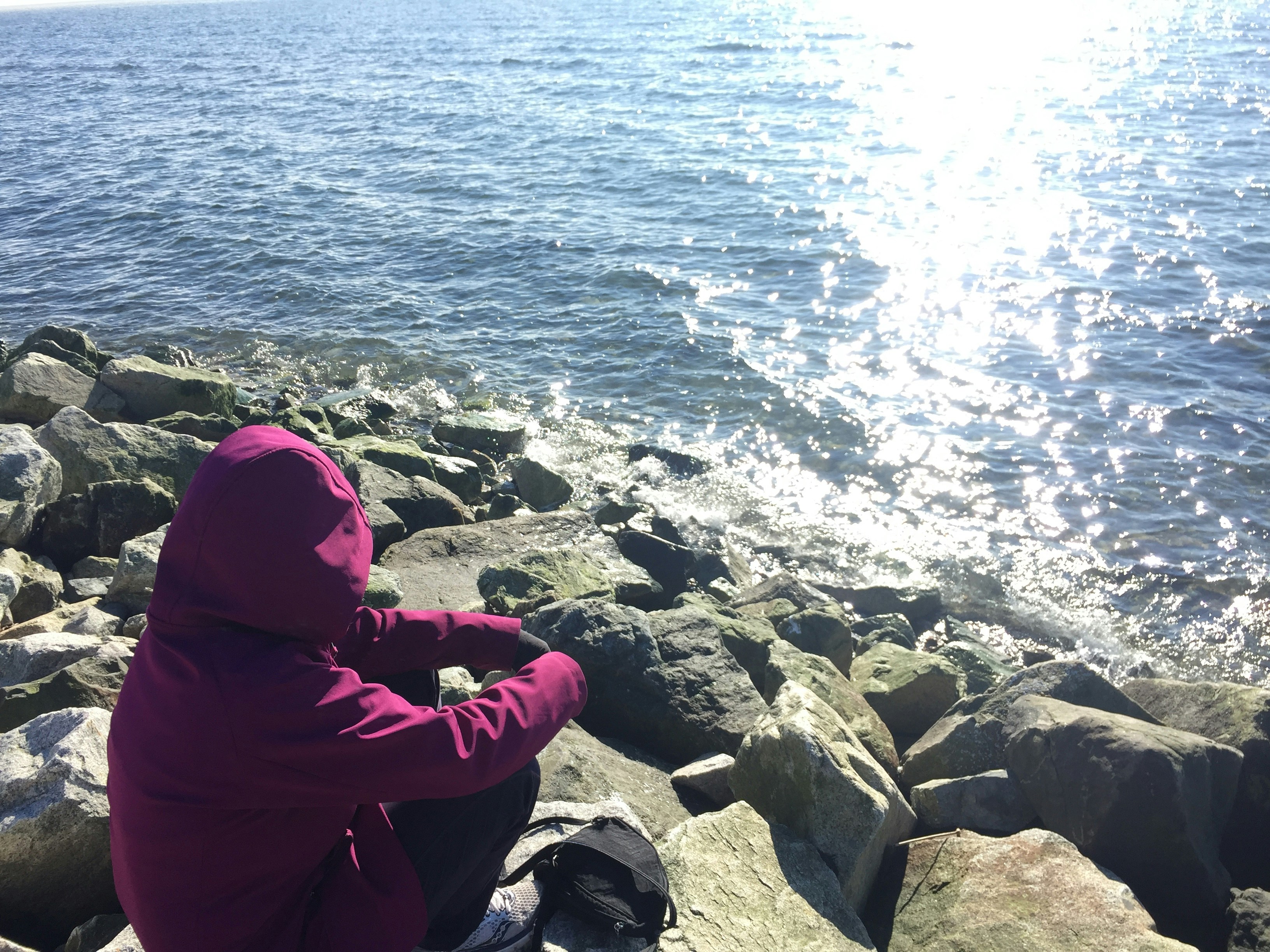 a person sitting on rocks near the water
