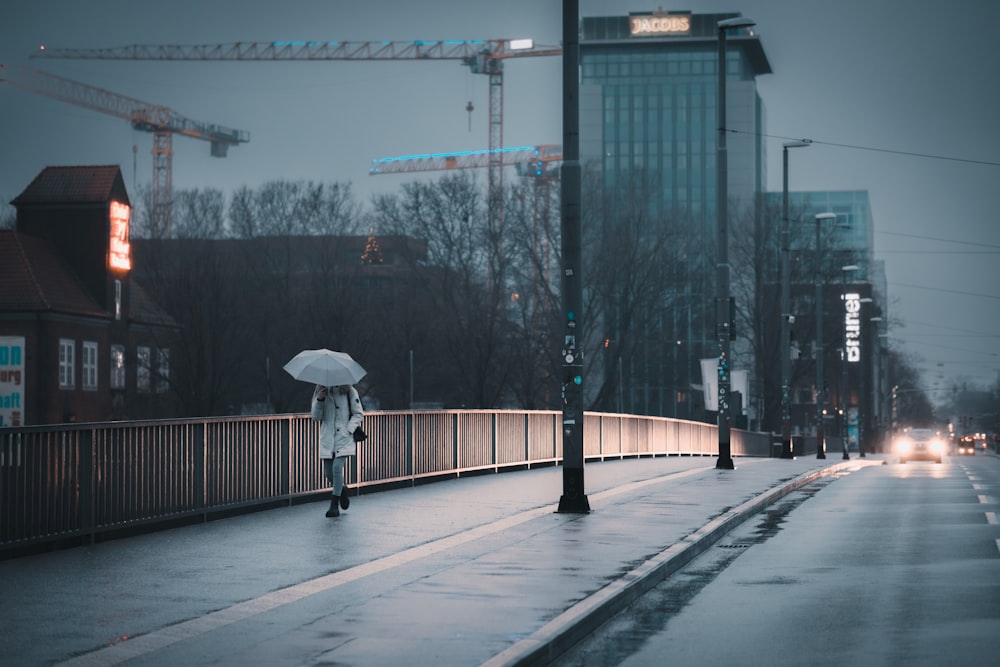 a person with an umbrella walking across a bridge