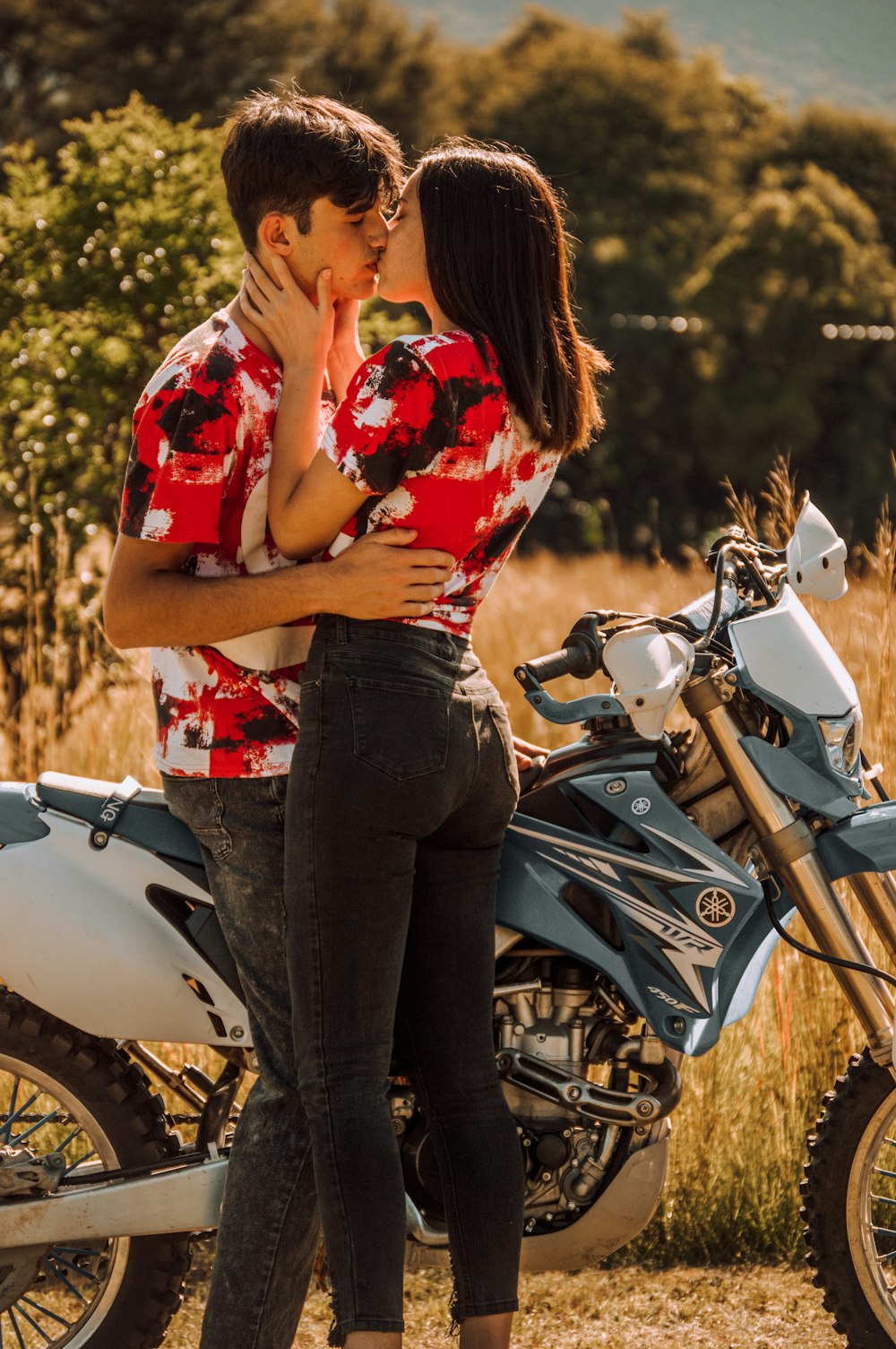 um homem e uma mulher se beijando ao lado de uma motocicleta