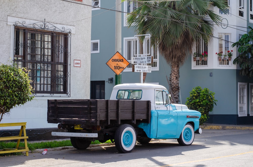 a blue and white truck parked on the side of a road