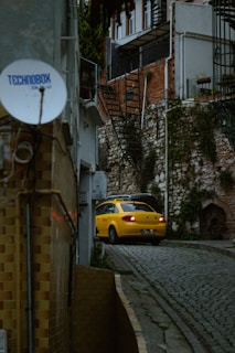a yellow car driving down a cobblestone street