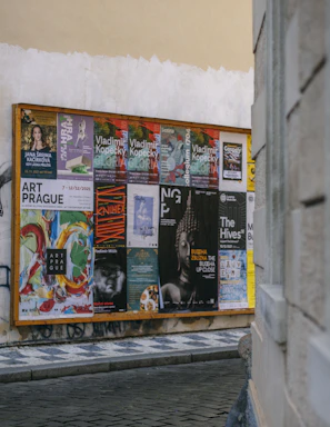 Close-up of hands signing in front of a community notice board filled with event posters and notices.