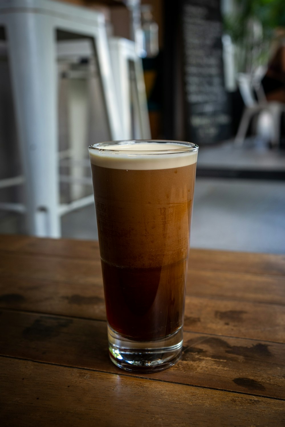 a glass filled with liquid sitting on top of a wooden table