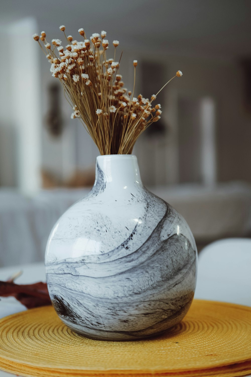 a white vase sitting on top of a yellow plate
