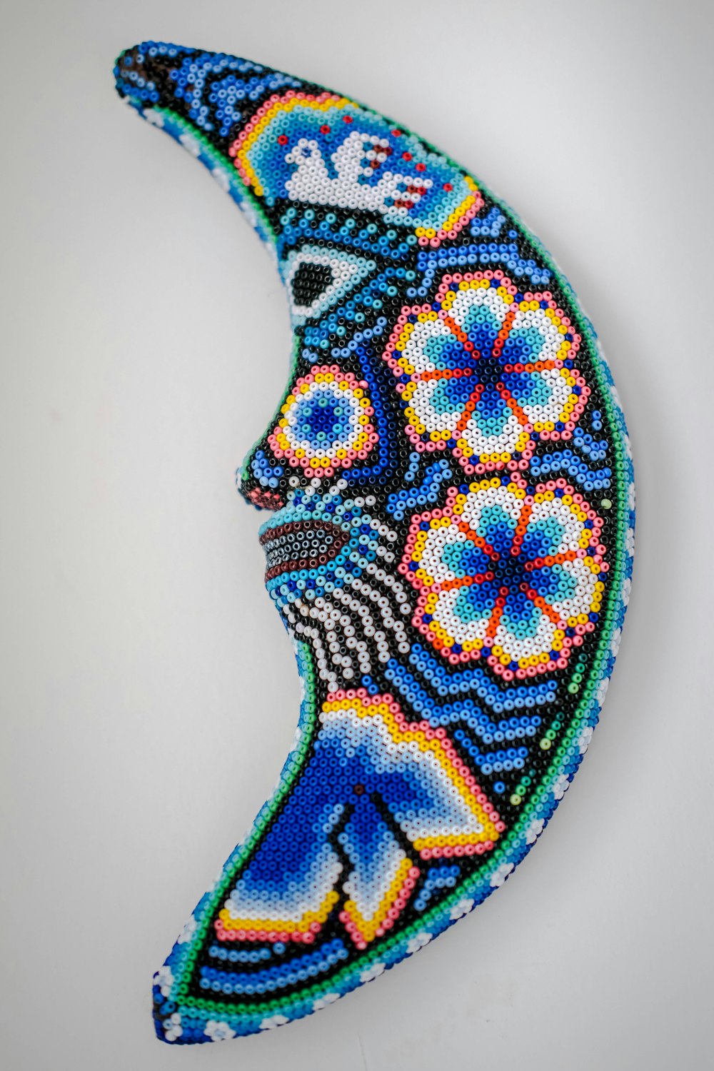 a beaded picture of a woman's face on a crescent