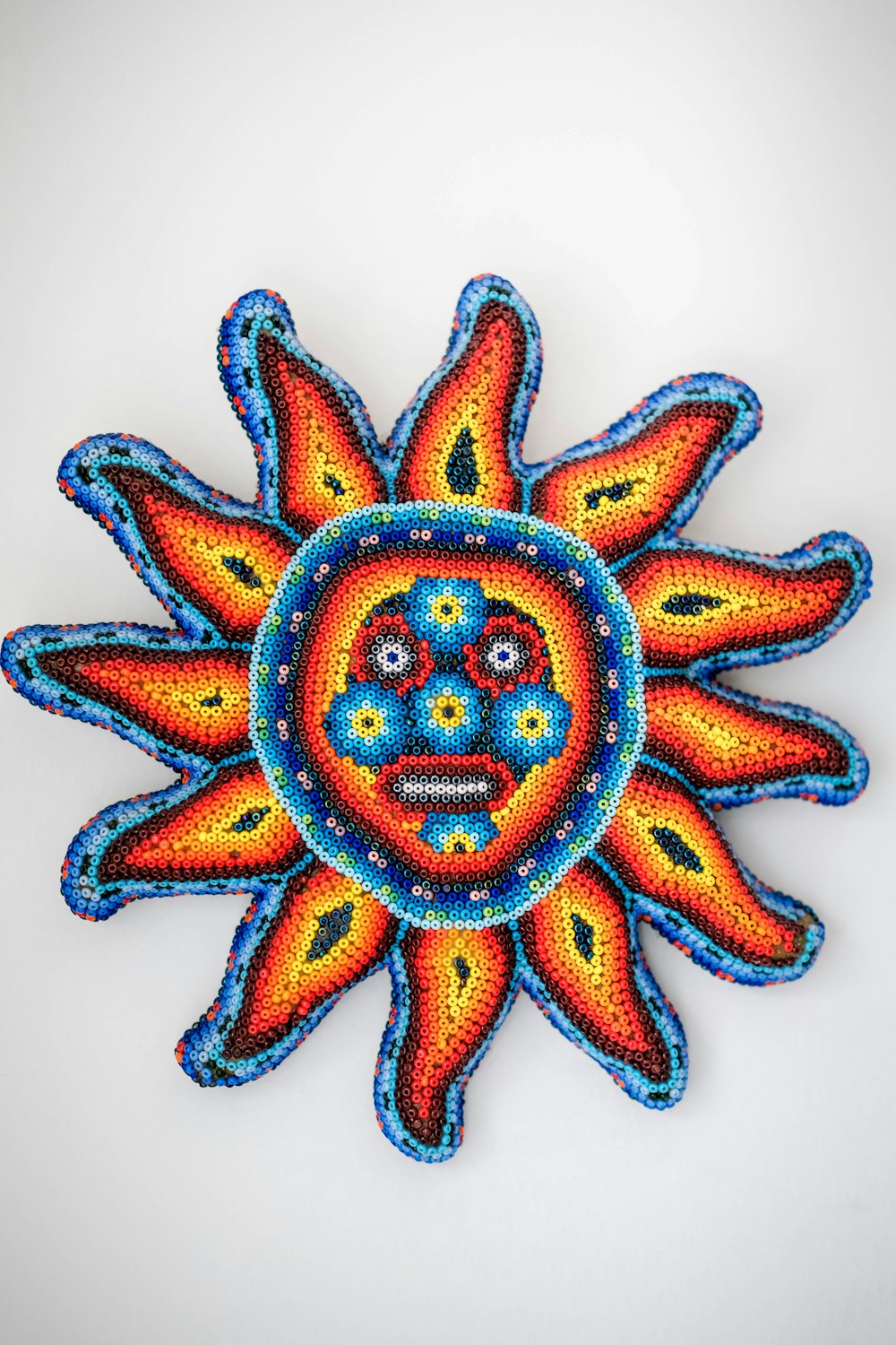 a colorful sun with a face made of beads