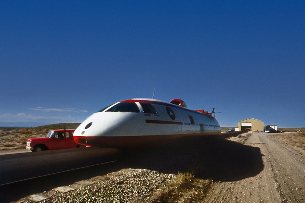 a white and red train traveling down a dirt road