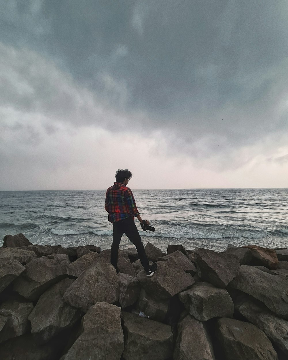 a person standing on rocks near the ocean