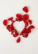 A close-up of dew-kissed red rose petals forming a heart shape on a wooden table.