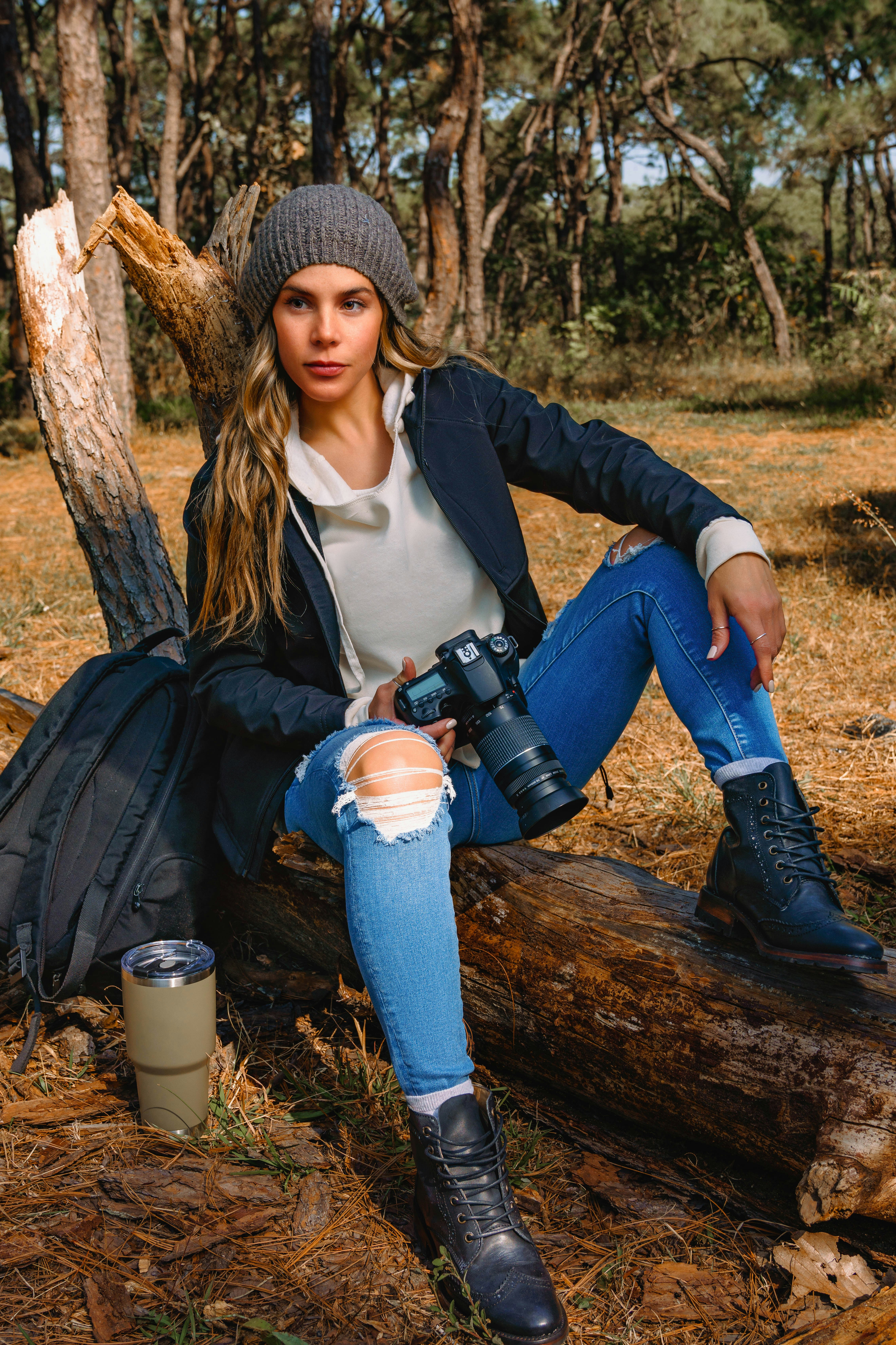 a woman sitting on a log with a camera