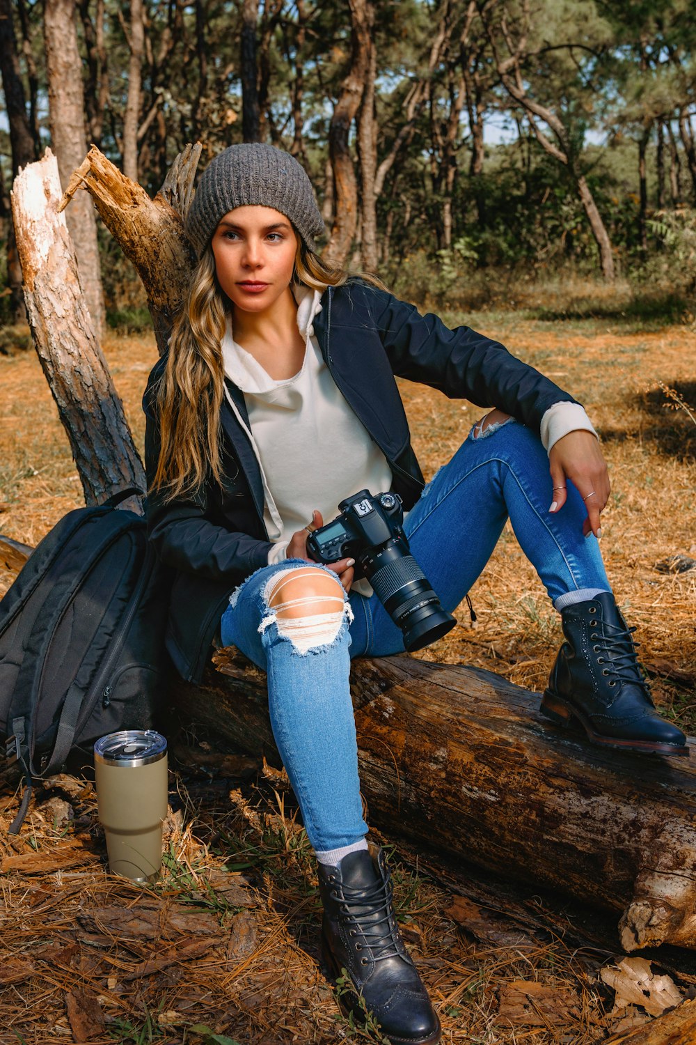 a woman sitting on a log with a camera