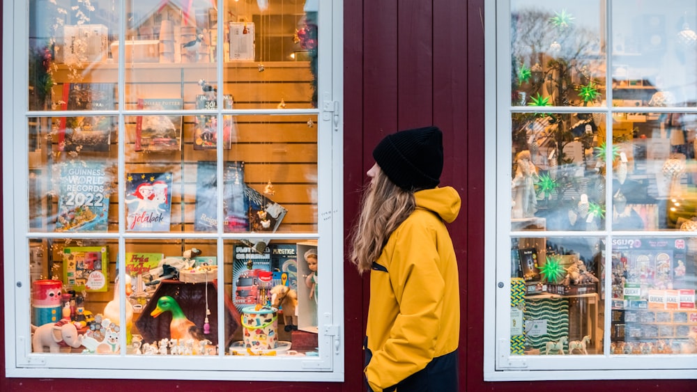 a person in a yellow jacket looking at a store window