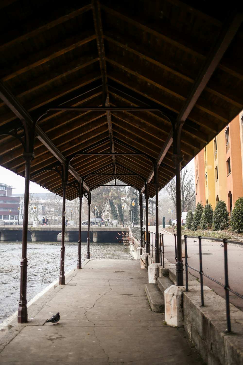 a covered walkway next to a body of water