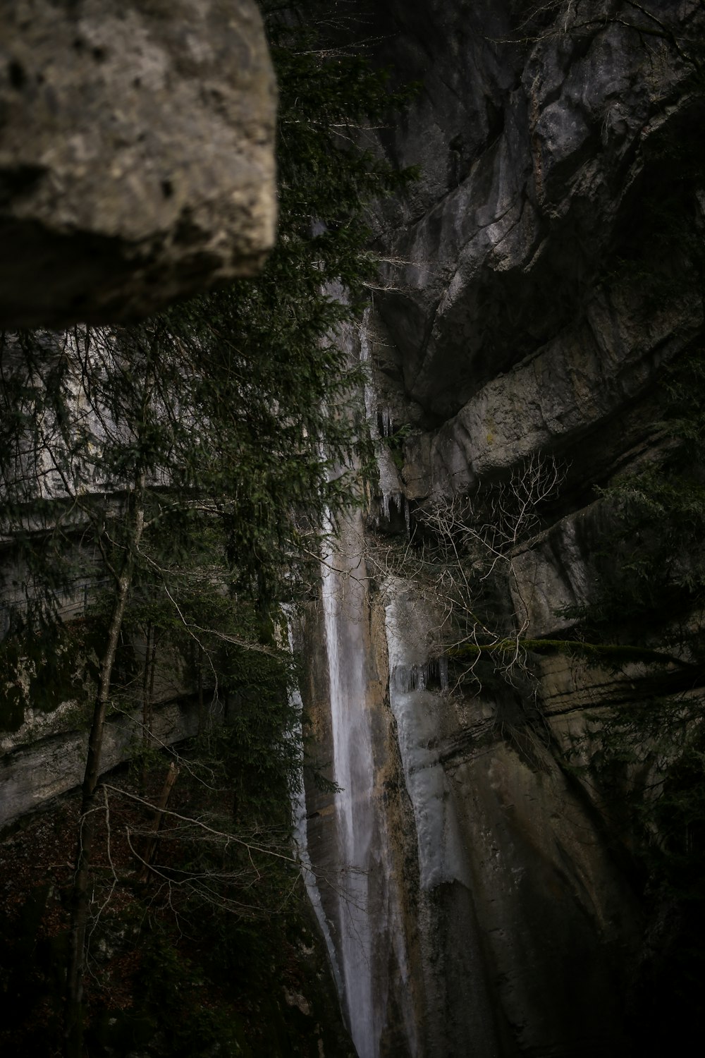 a man standing on top of a cliff next to a waterfall