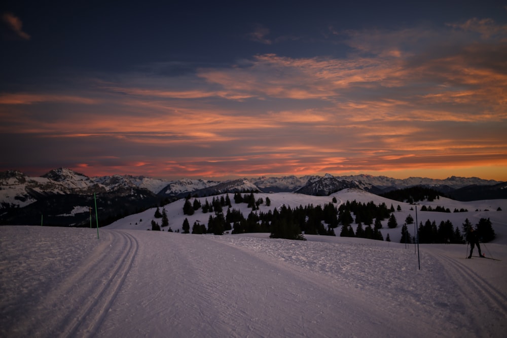 a sunset view of a ski slope with mountains in the background